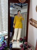 Woman wearing a mustard yellow printed cotton co-ord set with embroidered neckline and off-white wide-leg pants by Label by Pushp