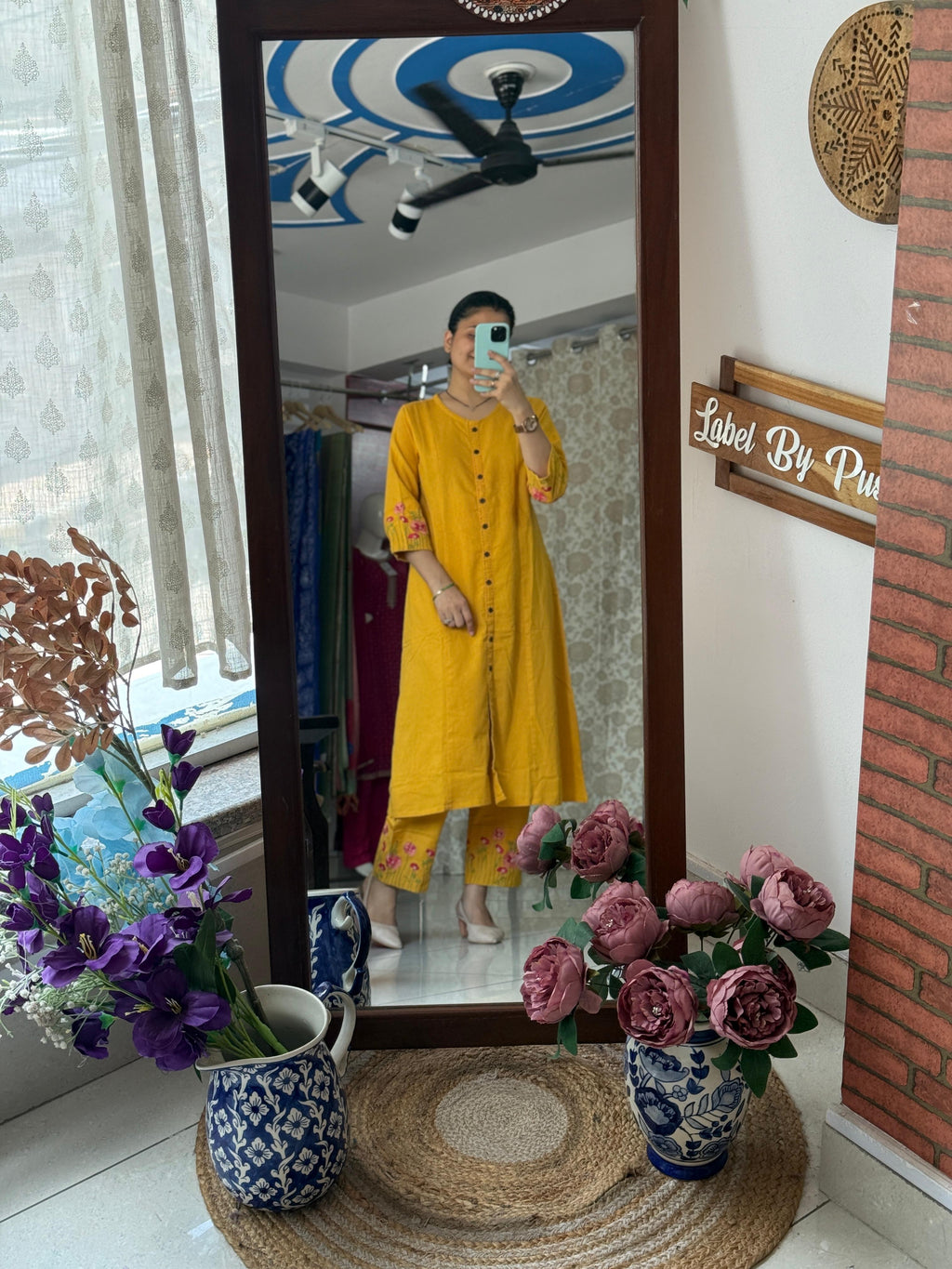 Woman wearing a mustard yellow embroidered cotton kurta set with floral embroidered sleeves, front button detailing, and matching embroidered straight pants by Label by Pushp